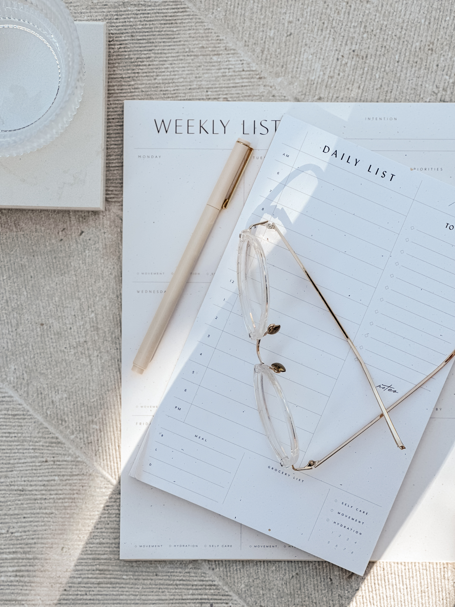 Minimal flat lay of weekly and daily planners with neutral pen and reading glasses on a textured linen surface – True North Visionaires